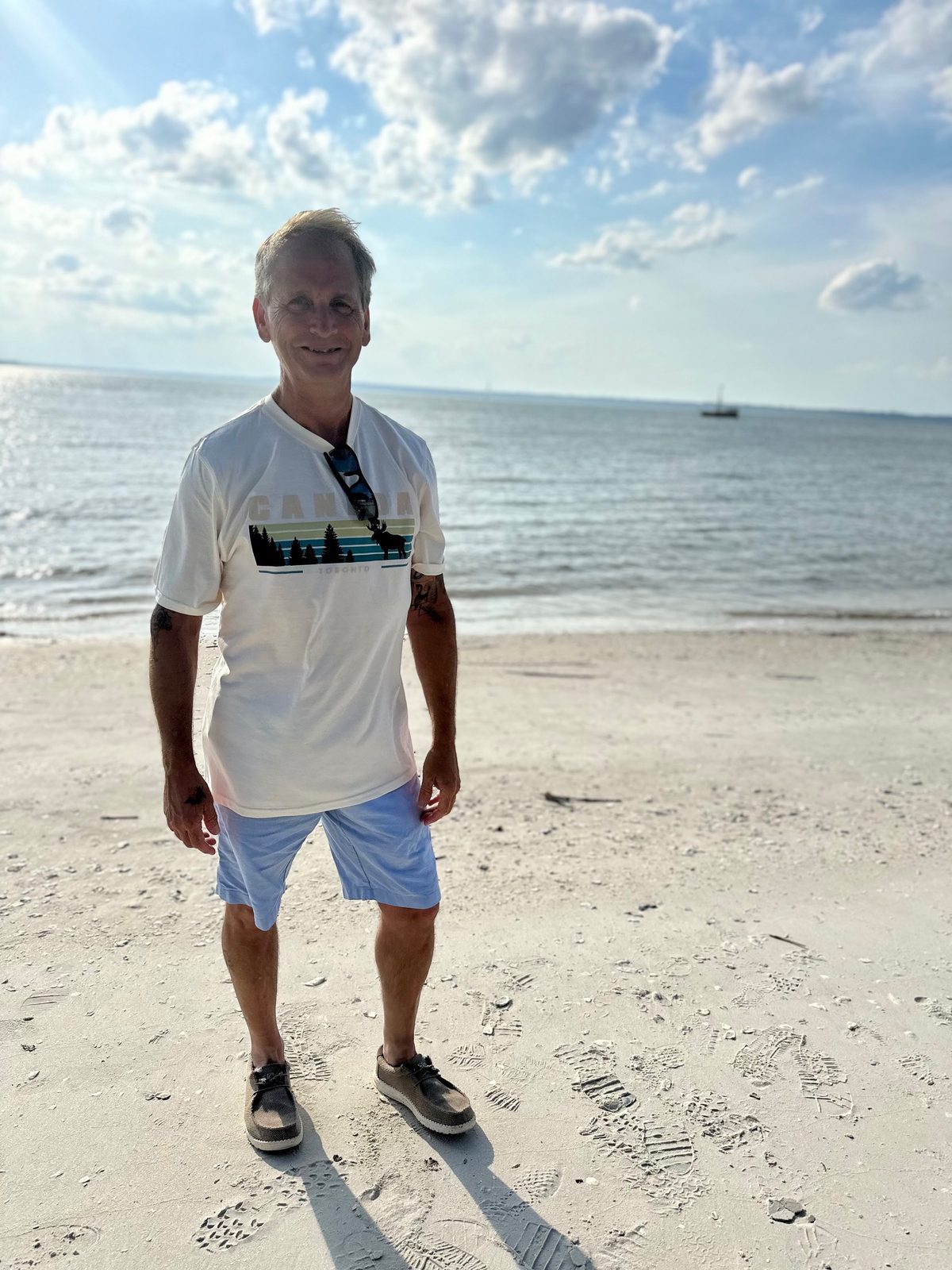 Brian standing on a sunny beach with the ocean behind him